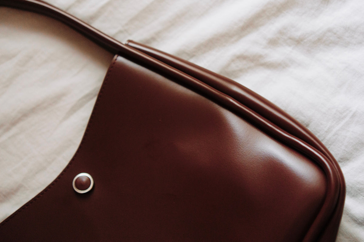 Sac en cuir brun posé sur un tissu clair