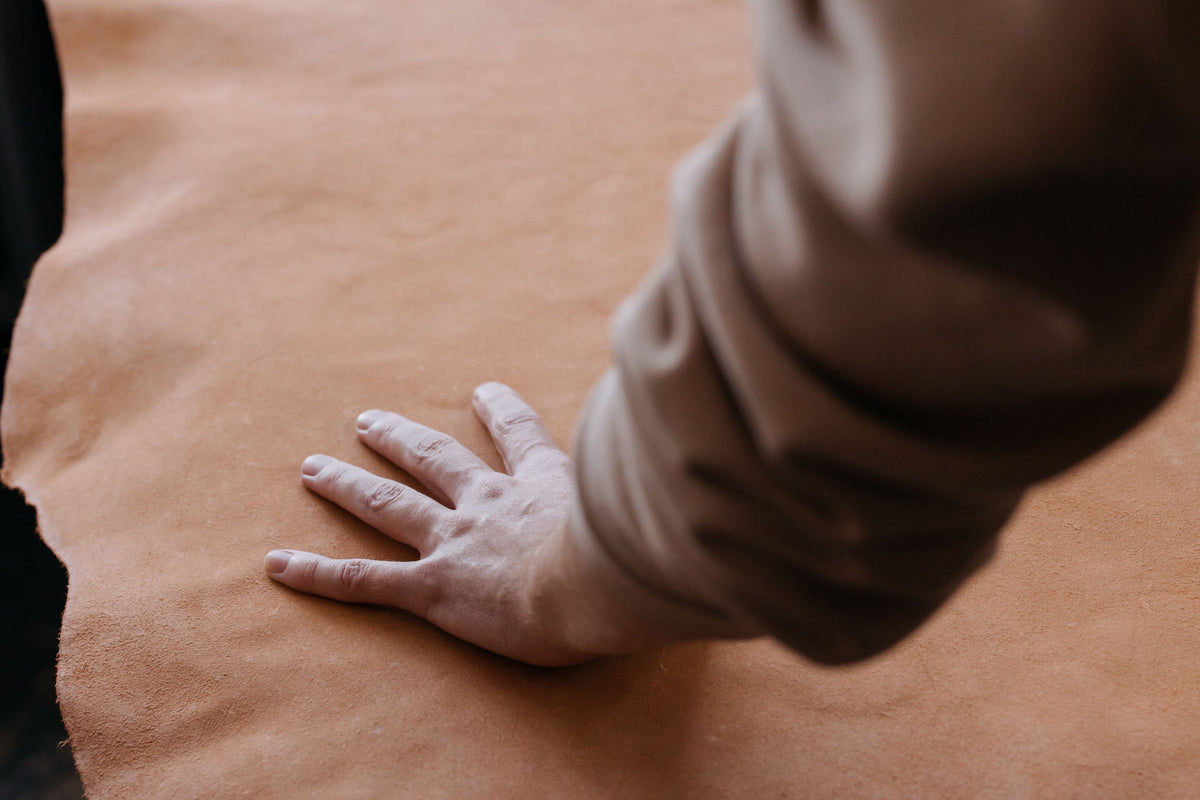 Main posée sur une pièce de cuir brun