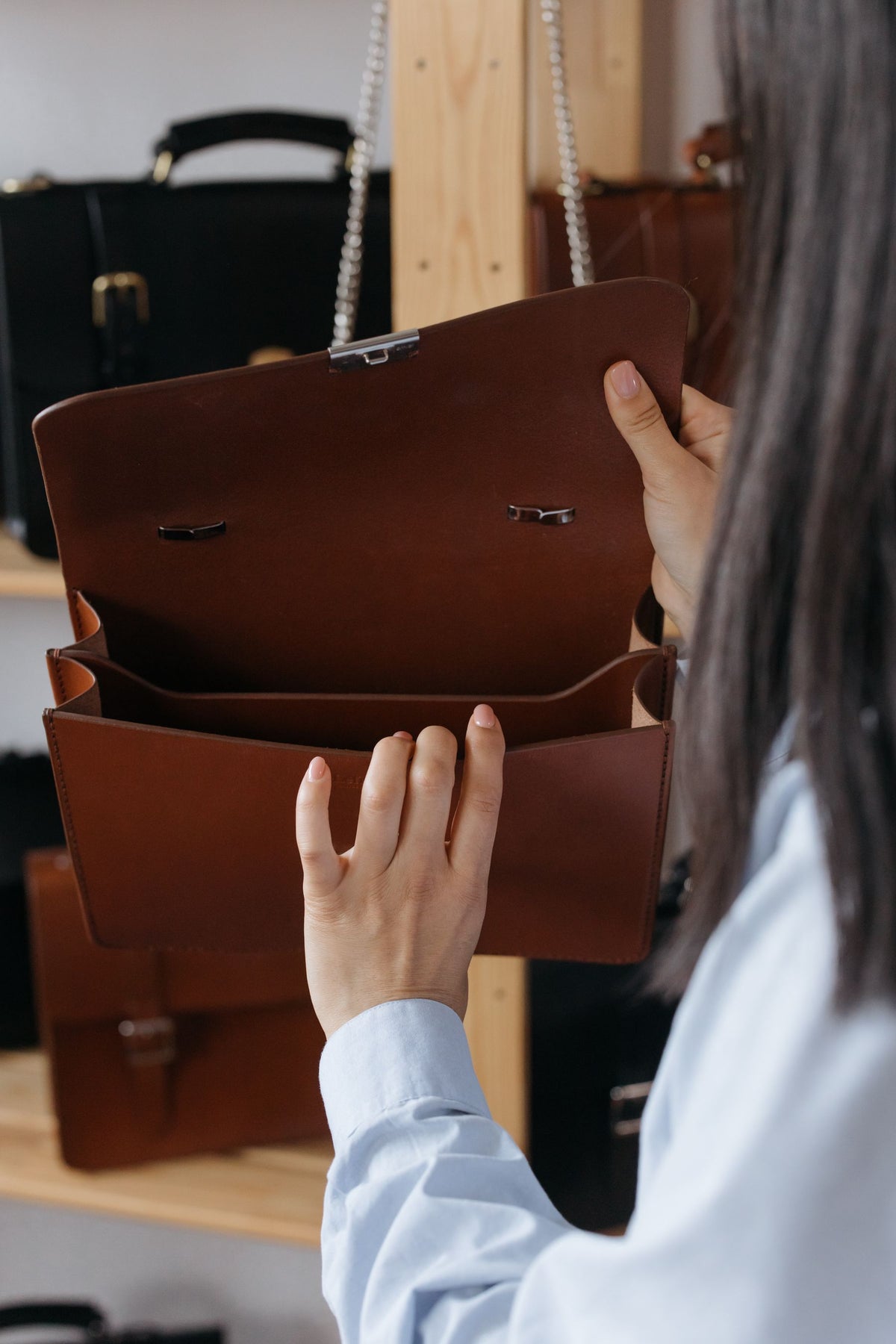 Personne examinant un sac à bandoulière brun ouvert