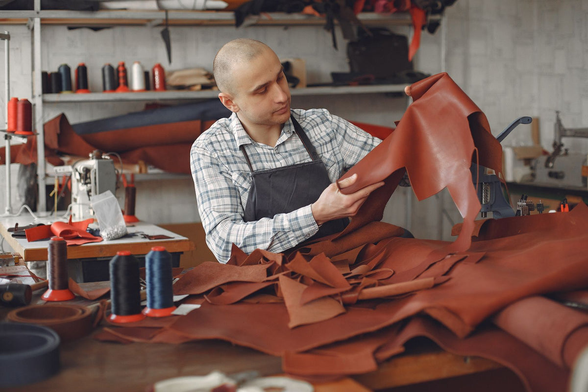 Artisan examinant une pièce de cuir dans son atelier.